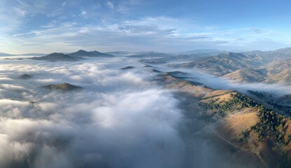 Obraz premium Aerial panorama of rolling hills and mountains partially obscured by a sea of low-lying clouds under a clear, bright sky