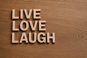 Fototapeta premium Inspirational Wooden Letters Arranged on a Wooden Surface Spelling: Live, Love, Laugh, Promoting Positivity