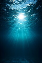 Fototapeta premium Sunlight streams through the ocean waves, creating a mesmerizing underwater scene of light rays and deep blue hues, capturing the beauty and tranquility of the sea