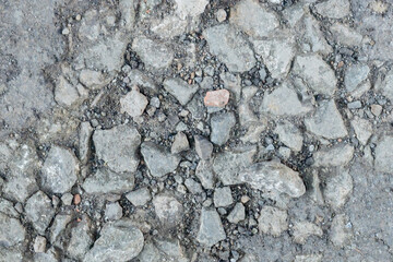 Close-up texture of rough stone and gravel surface, showing natural pattern of rocks and pebbles in...
