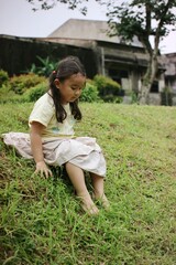 Fototapeta premium Young Girl Relaxing on a Grassy Hill in a Garden Setting