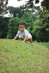Young Child Exploring Outdoors on a Green Hillside with Lush Background