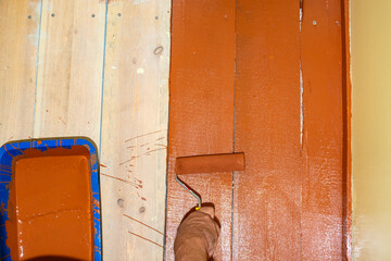 Roller painting of a wooden floor, background with paint on a wooden floor. Summer house renovation...