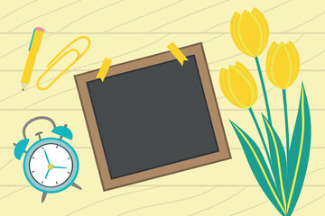 Yellow tulips on a light wood background with a blackboard pen paperclip and alarm clock flowers floral