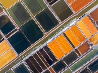 The ship transporting salt was sailing along the colorful salt fields. Salt-farm workers produce...