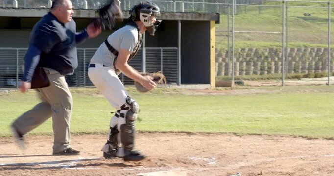 Pitch arriving, male players bunting ball sliding into home, catcher tagging and umpire calling out