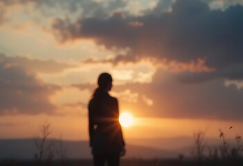Obraz premium Silhouette of woman at sunset with warm golden sky background