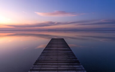 Obraz premium Wooden pier on calm water at sunset