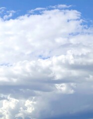 Naklejka premium Fluffy white cumulus clouds fill a mostly blue sky