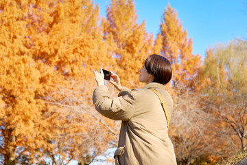 紅葉の写真を撮影する女性　ミドルエイジ