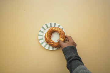 Hand reaching for a freshly baked bagel on a plate