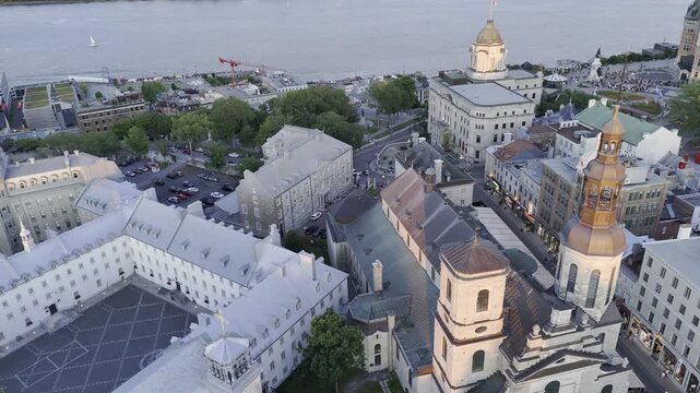 Drone with camera at sharp angle at sunset, flies east over Place de l'Hotel de Ville to St Lawrence River in Quebec City, Canada