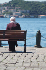  young woman sits by the water in sunny waterfront area