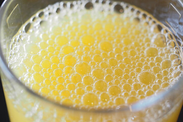 Freshly poured orange juice with bubbles in clear glass