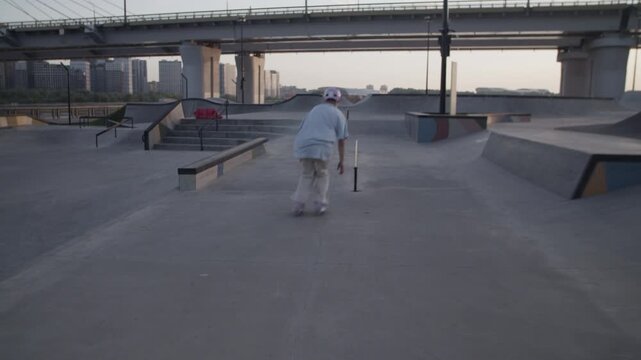 Sportive roller skater in helmet jumps on parapet and railings