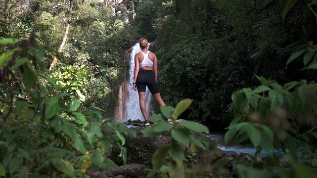 Woman standing on a large rock with las Gemelas Waterfalls cascading behind them.
