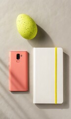 Flat lay of a coral smartphone a white notebook and a textured lime green object