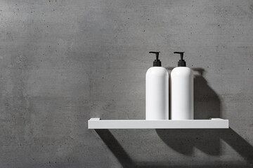 Two minimalist white bottles with black pump caps on white shelf against texture gray concrete...