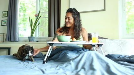 Woman petting cat while having breakfast in bed - Powered by Adobe