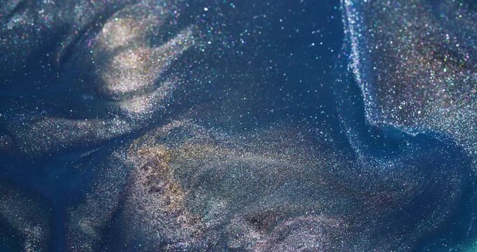 Glitter ink. Stream texture. Defocused blue silver golden color shiny liquid spatter spreading on abstract creative acrylic background.