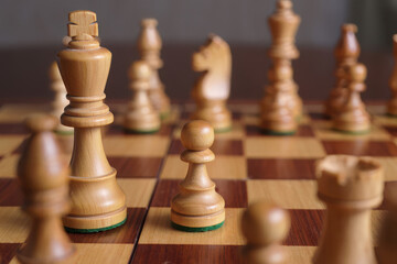 Close up of wooden chess pieces on a chessboard ready for play
