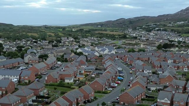 North Wales red brick modern housing neighbourhood under Holyhead mountain aerial view moving right