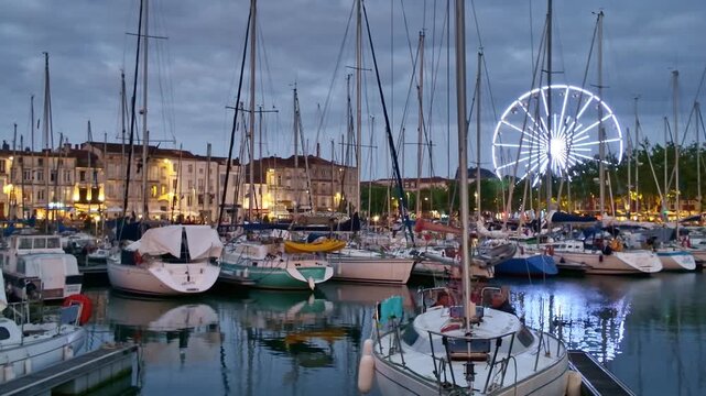 Panoramic view of sunset night with boats at Quai Valin and illuminated Ferris wheel, La Rochelle, Charente-Maritime, France.