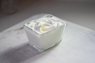 A stylish glass container filled with smooth whipped cream on a marble surface.
