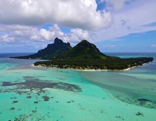 Aerial view of tropical island, lush green hills, turquoise water, and coral reefs