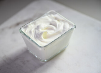 A fresh creamy yogurt in a glass bowl on a clean marble surface.