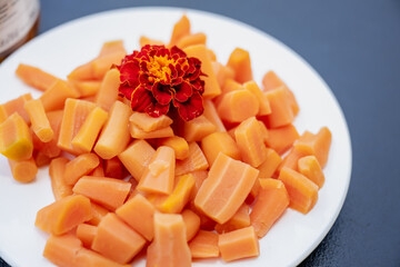 Plate of vibrant carrot snacks garnished with a marigold flower.