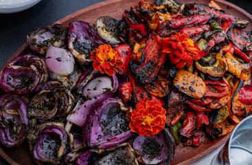 Grilled vegetables platter, beautifully arranged with colorful flowers.