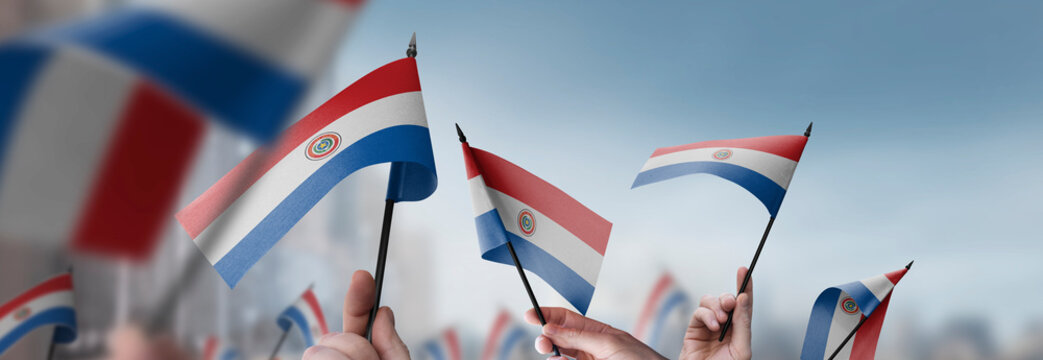 Paraguay flags in their hands on a blurred urban background