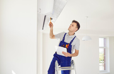 Specialist technician is performing maintenance or repair on an air conditioner at home or in an...