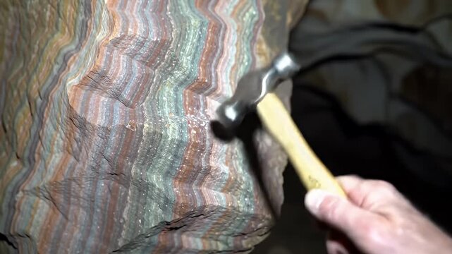 A hammer hits a stripy stone