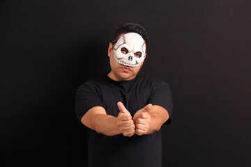 Man wearing a skull mask like Catrin to celebrate the traditional Mexican Day of the Dead shows the...