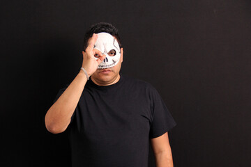Man wearing a skull mask like Catrin to celebrate the traditional Mexican Day of the Dead shows the...