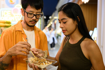 Young couple enjoying food at night market in asia