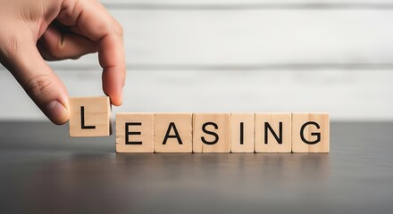Hand placing letter blocks to spell out the word leasing
