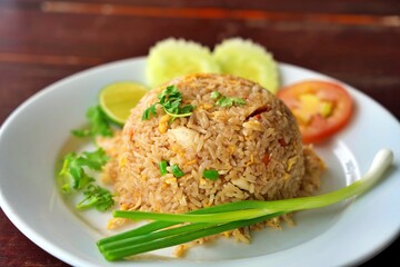Crab fried rice garnished with coriander, sliced tomato, cucumber, and lime. Thai crab fried rice