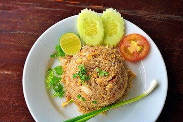 Crab fried rice garnished with coriander, sliced tomato, cucumber, and lime. Thai crab fried rice, Top view