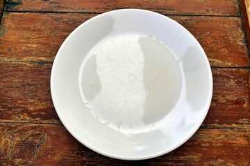 Empty plate on brown wooden table in natural light, Top view