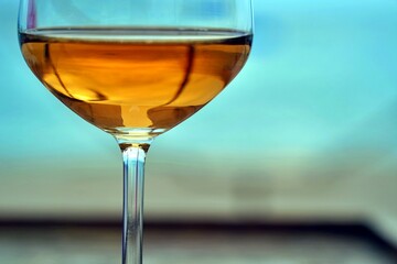 Rosé wine glass with golden sea reflection inside the wine Close up