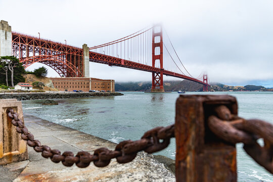 View from the shore of a red Bridge amidst foggy conditions.