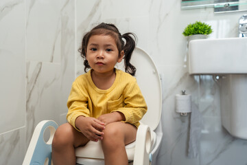 toddler girl is sitting on toilet at home. potty training and learning