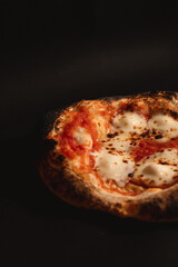 Close-up view of mozzarella pizza on a black background.