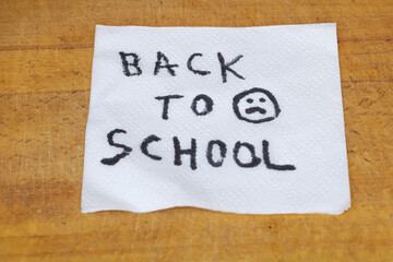 Handwritten Back to School Message on Paper Towel over Wooden Surface