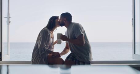 Kiss, love and coffee with couple at window of home for connection, romance and peace. Relax,...