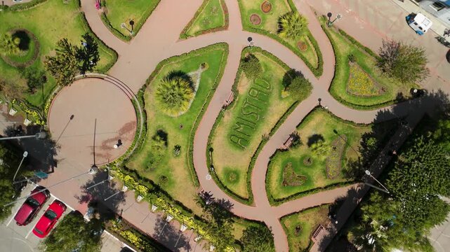 Dynamic top down aerial shot spins over the geometric patterns of Parque de la Amistad in Huaraz, creating a hypnotic spiraling birds eye view of the public park