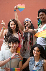 Portrait of a group of young people celebrating gay pride holding rainbow flags and heart shape